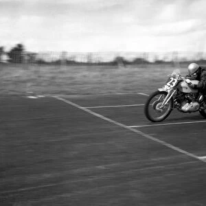 John Surtees speeds over the finishing line at the race track on his Vincent motorbike