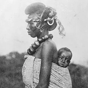 A lady of smart society in French Guinea with her baby on her back. She belongs