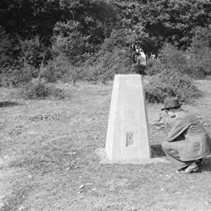 A man crouching at a boundary post in Kemsing, Kent. 1938