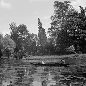 A man in his long boat rowing along the Boating Pool, Mill Garden, River Leam
