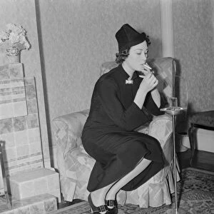 Miss Muriel Oxford sits by the fire having a cigarette