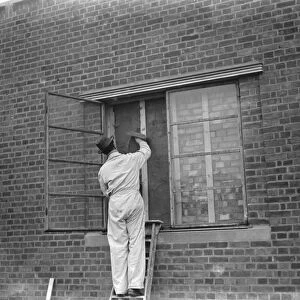 A modern police station on Wellhall Road, Eltham, London. A worker is plastering over a window