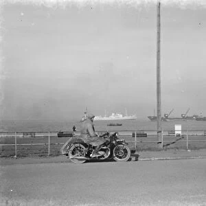 A motorcyclist looks out at the traffic on the Thames estuary from Gravesend promenade