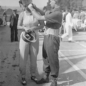Mr A. C Dobson adjusting his wifes helmet before she took the track in her Fiat