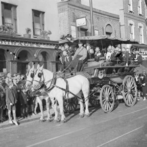 An old stagecoach crammed with passengers rolling down Deptford High Street