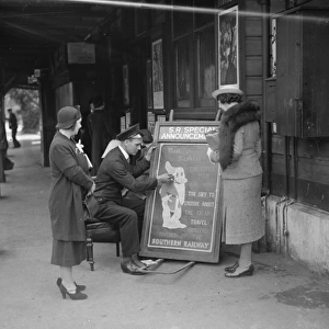 People gather round to watch the railway porter sign writer Mr E A Burgar. 1938