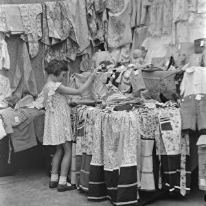 Petts Wood fete in Kent. A little girl at a garment stall. 1937