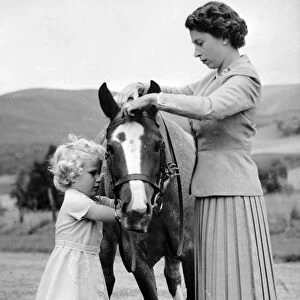 Princess Anne helps her mother Queen Elizabeth to adjust the bridle of the pony Greensleeves