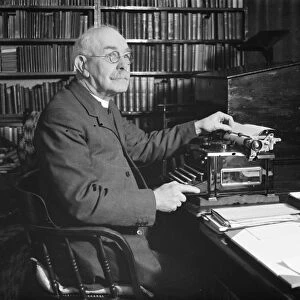 The Reverand Mackintosh of Horns Cross, Kent, sitting at his typewriter