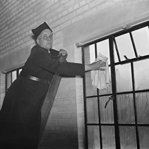 The Reverend M Cox cleaning windows in Swanscombe, Kent. 1937