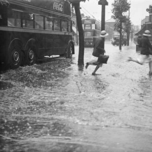 Schoolchildren running through the floods at the junction of Forest Road and Chingford