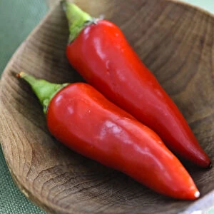 Shiny red chilli peppers in big wooden spoon credit: Marie-Louise Avery / thePictureKitchen