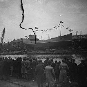 Spectators wait to see the new ship launch as the ship sits broadside on the slipway