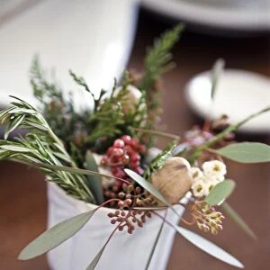 Table decoration of herbs, berries and greenery on small white cup credit: Marie-Louise