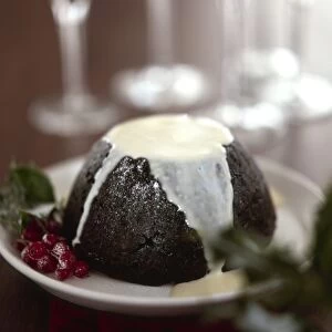 Traditional British Christmas pudding with thin cream or custard poured over