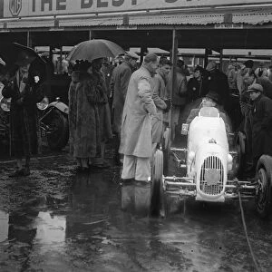 Umbrella as hood at rain sodden Brooklands. Heavy rain caused disappointment to