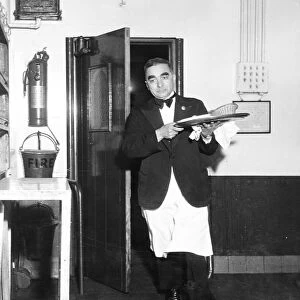 A waiter rushes through the kitchen door with a tray of food during the rush for orders at lunch