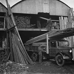 A Walter Lane Bedford lorry loads up with planks of wood at their sawmill in Sidcup