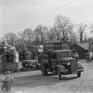 Workers loading wooden crates onto a Bedford truck belonging to E James and Son