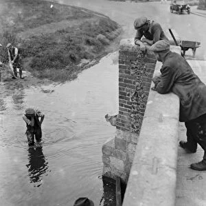 Workmen wade through the water crossing at the Eynsford bridge over the River Darent