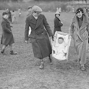 A young fan being carried to the races at the R A Woolwich point to point by baby carrier