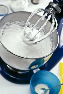 Beaten egg white in stainless steel mixer in kitchen setting, showing stiffness Beaten egg white in stainless steel mixer in kitchen setting, showing stiffness