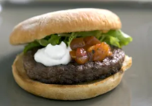 Chargrilled hamburger in bun with frisee salad, tomato salsa and sour cream credit Chargrilled hamburger in bun with frisee salad, tomato salsa and sour cream credit