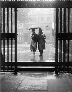 A couple walking in the rain under an umbrella in Deans Yard, Westminster Abbey A couple walking in the rain under an umbrella in Deans Yard, Westminster Abbey