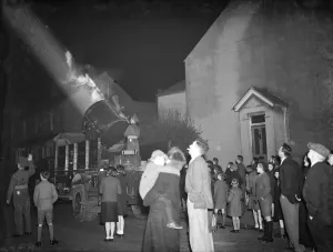A crowd watching the mobile Army searchlight as it progresses down their street A crowd watching the mobile Army searchlight as it progresses down their street