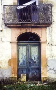 Crumbling, dilapidated entrance doorway and balcony of old French maison de maitre Crumbling, dilapidated entrance doorway and balcony of old French maison de maitre
