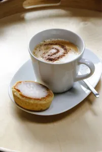 Cup of cappuccino with spiral of cocoa dusted on top with Swedish almond tart credit Cup of cappuccino with spiral of cocoa dusted on top with Swedish almond tart credit