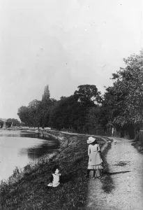 Two girls playing by the river bank, one girl with her hoop ready for rolling Two girls playing by the river bank, one girl with her hoop ready for rolling
