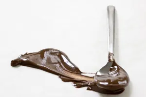 Melted chocolate smeared across white surface with a spoon leaving a plume shape Melted chocolate smeared across white surface with a spoon leaving a plume shape