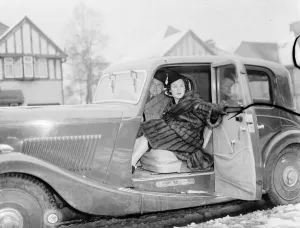 Miss Muriel Oxford sitting in the passenger seat of a car at the side of the road. 1937 Miss Muriel Oxford sitting in the passenger seat of a car at the side of the road. 1937