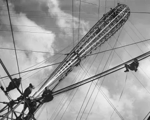 At Olympia, London, England, men on the job scramble about on thin cables At Olympia, London, England, men on the job scramble about on thin cables