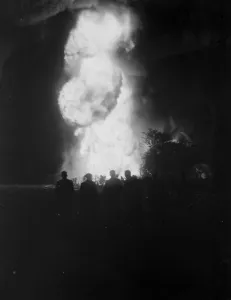 The silhouetted figures of men can be seen against the flames and smoke from the The silhouetted figures of men can be seen against the flames and smoke from the