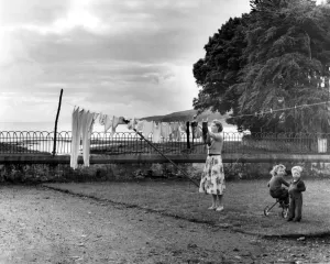 Washing day at one of the cottages, a mother pegging out the clothes, Island of Washing day at one of the cottages, a mother pegging out the clothes, Island of