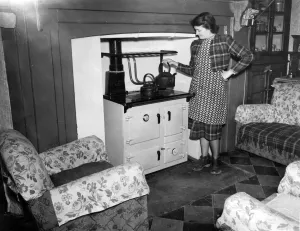 A woman boils to kettle for her cup of tea, in the main room of her cottage. The A woman boils to kettle for her cup of tea, in the main room of her cottage. The