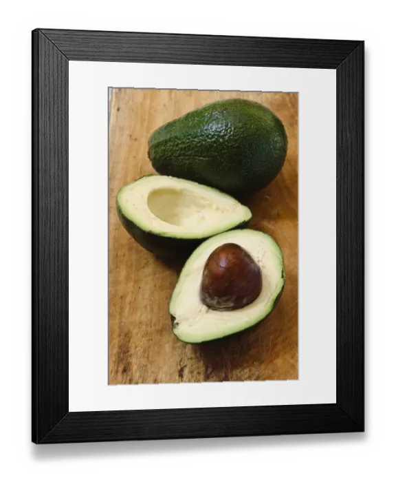 Framed Print : Whole and cut fresh avocado pear on wooden background credit: Marie-Louise Avery