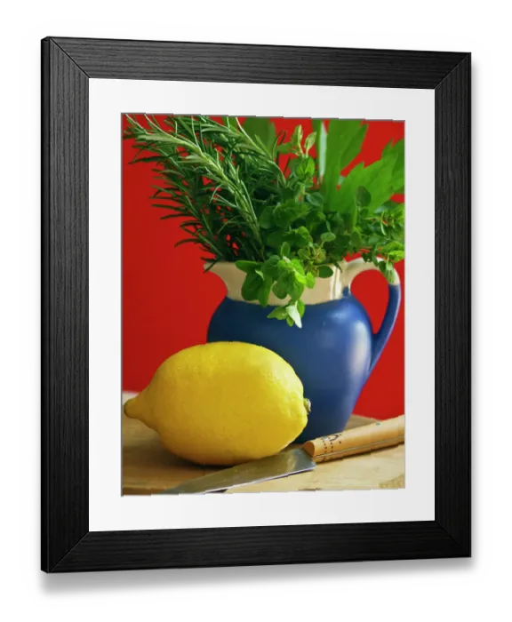 Framed Print : Lemon on chopping board with knife and bunch of mixed garden herbs in blue jug against Framed Print : Lemon on chopping board with knife and bunch of mixed garden herbs in blue jug against