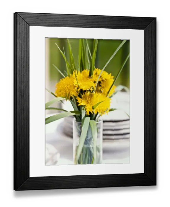 Framed Print : Bouquet of dandelions and long blades of grass in tall glass as table decoration credit