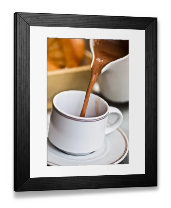 Framed Print : Pouring hot chocolate from jug into cup and saucer on cafe table, France, with brioche Framed Print : Pouring hot chocolate from jug into cup and saucer on cafe table, France, with brioche
