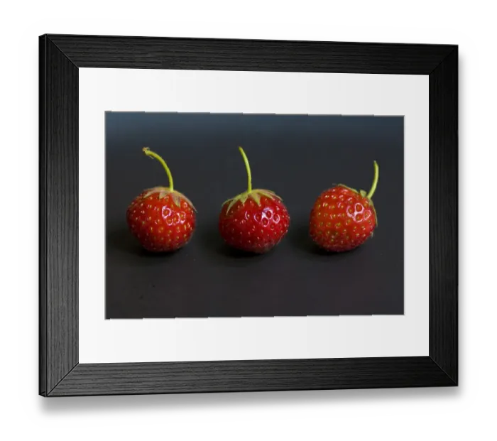 Framed Print : Three small strawberries in a row on black plate credit: Marie-Louise Avery  /  thePictureKitchen