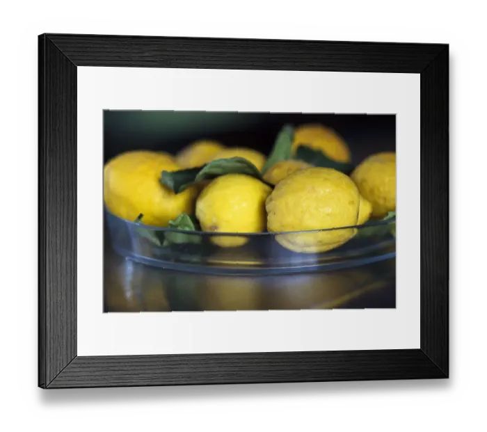 Framed Print : Natural, mediterranean lemons with leaves in glass dish on stainless steel counter
