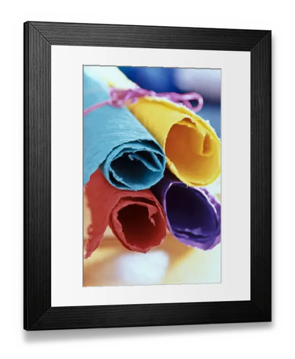 Framed Print : Four pieces of brightly coloured handmade paper rolled up and tied with pink string Framed Print : Four pieces of brightly coloured handmade paper rolled up and tied with pink string