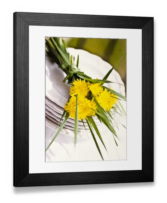 Framed Print : Bouquet of dandelions and long blades of grass on stack of white plates as table Framed Print : Bouquet of dandelions and long blades of grass on stack of white plates as table