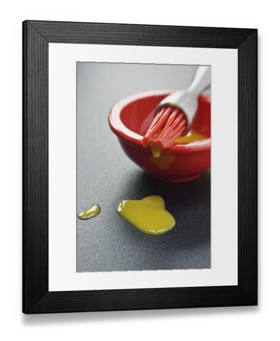 Framed Print : Egg yolk in small red bowl and dripping off red silicone bristles of modern pastry Framed Print : Egg yolk in small red bowl and dripping off red silicone bristles of modern pastry