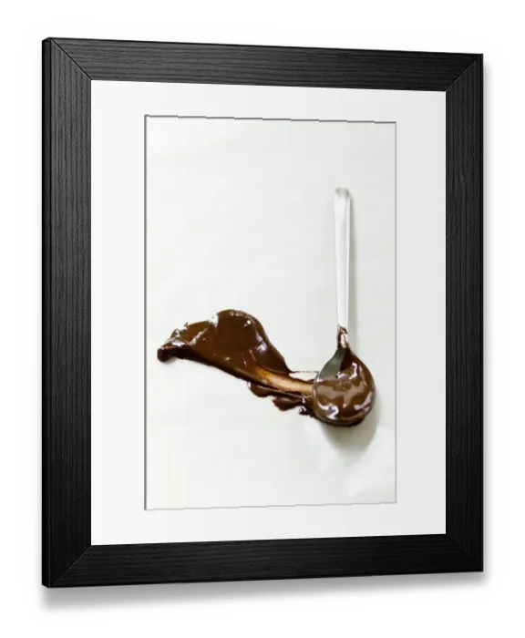 Framed Print : Melted chocolate smeared across white surface with a spoon leaving a plume shape Framed Print : Melted chocolate smeared across white surface with a spoon leaving a plume shape