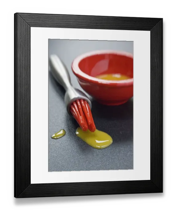 Framed Print : Egg yolk in small red bowl and dripping off red silicone bristles of modern pastry Framed Print : Egg yolk in small red bowl and dripping off red silicone bristles of modern pastry