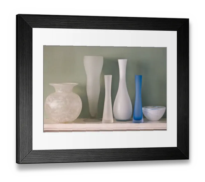 Framed Print : A collection of ground glass vases on mantel shelf, against, green wall credit